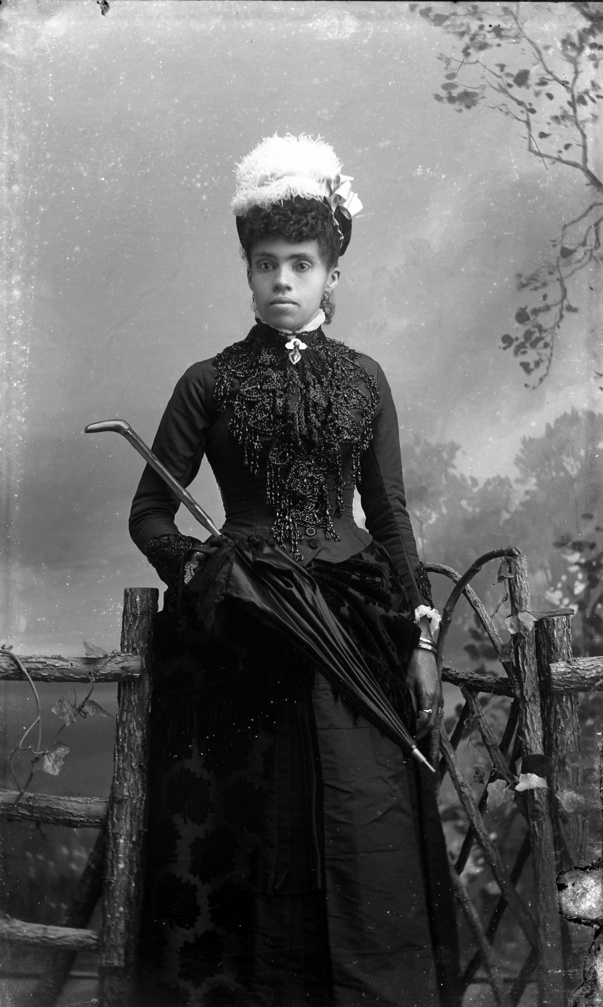 Woman wearing beaded dress and hat with feather.