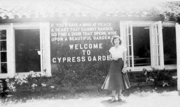 Unidentified lady stands in front of the sign for Cypress Gardens - Winter Haven, Florida 