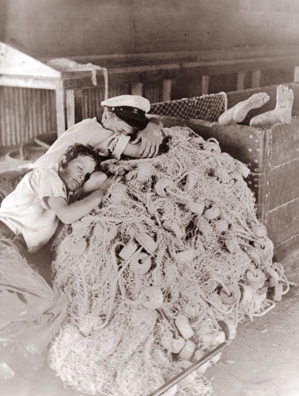 Boys sleep in the fish house on the idle nets.