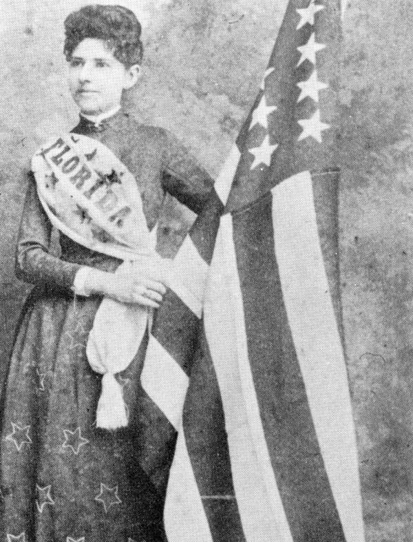 Mena E. Williams Hirshberg stands by a U.S. flag - Tallahassee, Florida