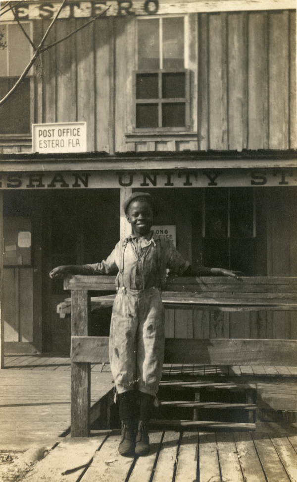 Postcard with a portrait of an African American boy in front of the Unity's first store building.