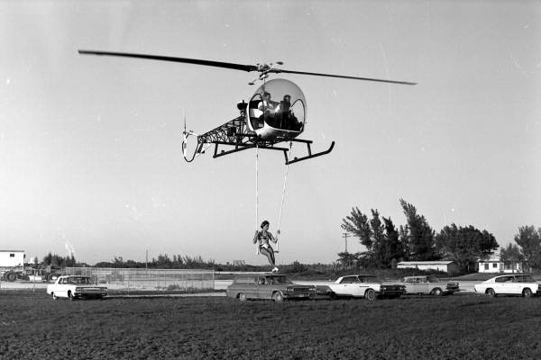 Girl from circus riding beneath helicopter - Key West, Florida.