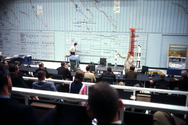 Man with rocket models speaking to audience at Cape Canaveral.