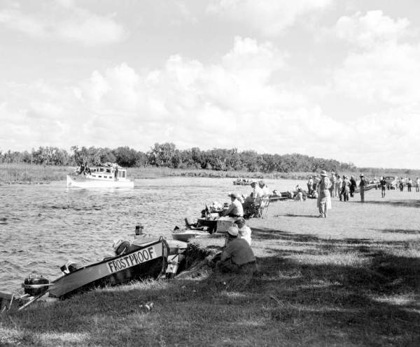 View of a crowd watching a boat traveling on the Kissimmee River