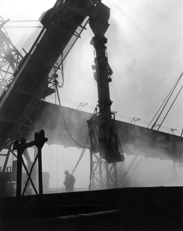 Telescopic chute is lowered into cargo hold to load ship..