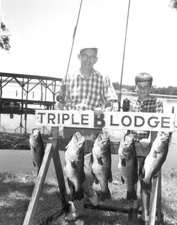 Gordon Hamilton and Tom Dodamead pose with their catch of bass hanging from the Triple B Lodge sign - Welaka, Florida.