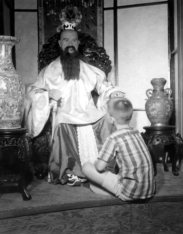 A boy sits in front of an Oriental figure displayed at Potter's Wax Museum - Saint Augustine, Florida