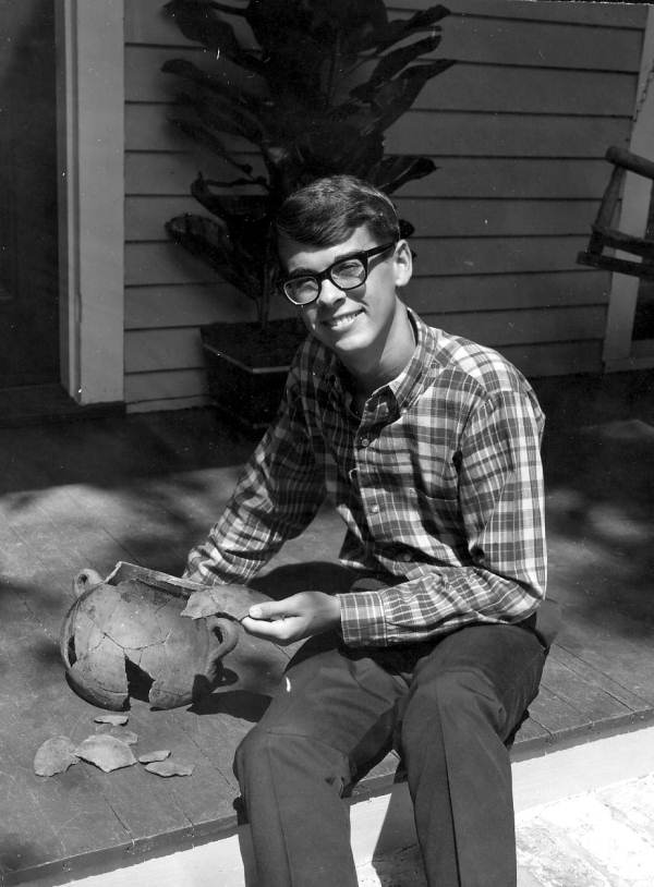 A young man reconstructing pottery on a porch - Pensacola, Florida.