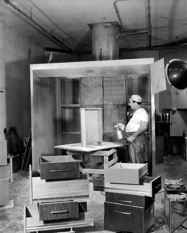 Furniture workers spray lacquering desk drawers - Miami, Florida .