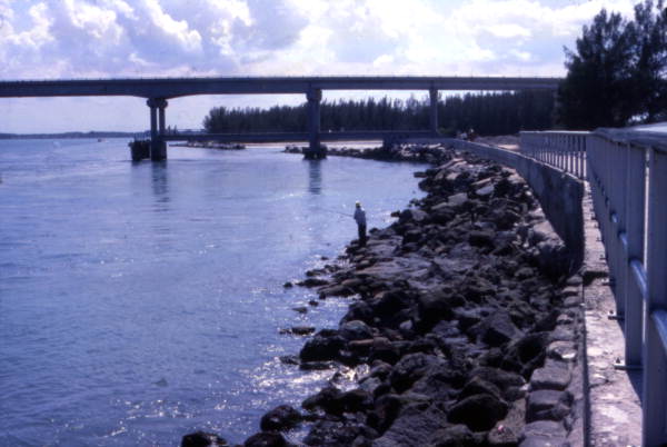 View looking toward person fishing from rocks near the bridge at Sebastian Inlet State Park - Melbourne Beach, Florida.