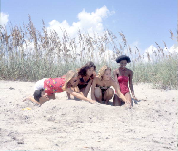 Young women burying a man in the sand at the beach - Hutchinson Island, Florida