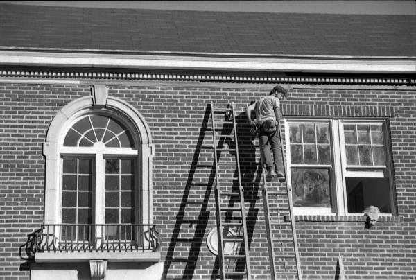 Worker on a ladder works on a building - Tallahassee, Florida.