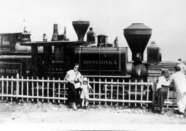 Mother and child standing by Northern Pacific's first engine