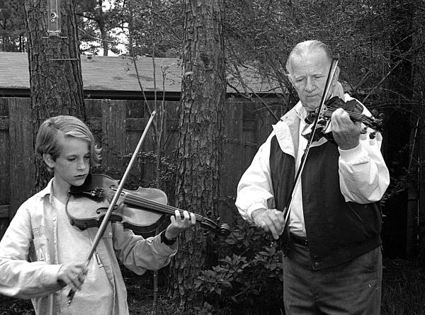 Apprentice Andrew Cook learning the art of twin fiddling from his mentor George Custer.