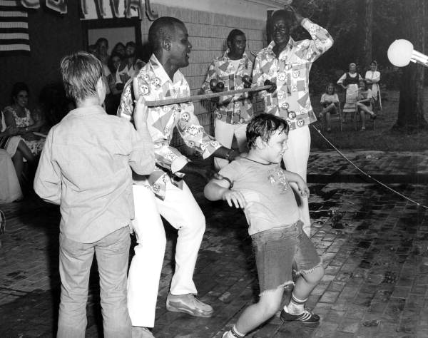 The Junkanoos, Bahamian folk group from Key West, teaching boy to limbo dance at the 1977 Florida Folk Festival - White Springs, Florida