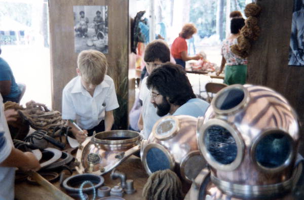 Nick Toth with display of Greek deep sea diving helmets at the 1986 Florida Folk Festival - White Springs, Florida