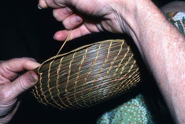 Hands of a Creek Indian weaving a pine needle coil basket
