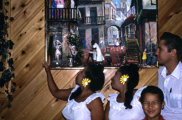 Sahara, Haydee, and Michael Scull looking at one of their paintings while Michael Blundio smiles at the camera - Miami Beach, Florida.