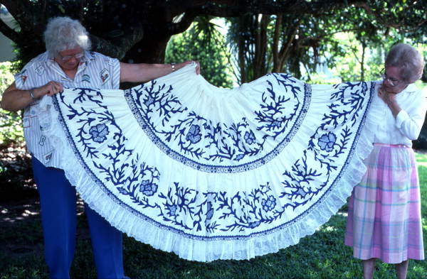 Two women holding up an example of reverse applique needlework done by Fula Peleti