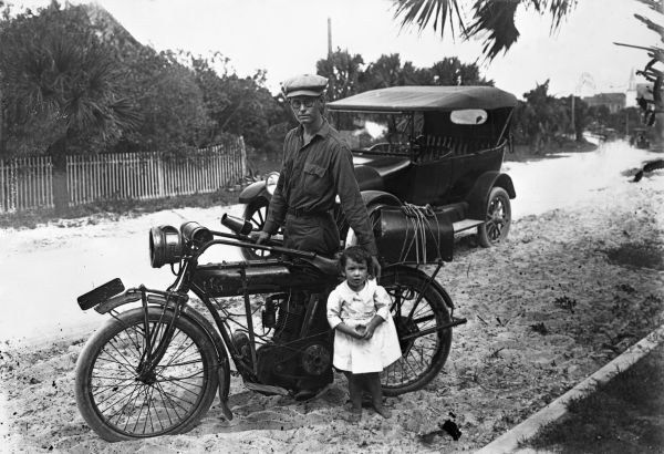 Lowell Hill and daughter showing off his Indian motorcycle and car.