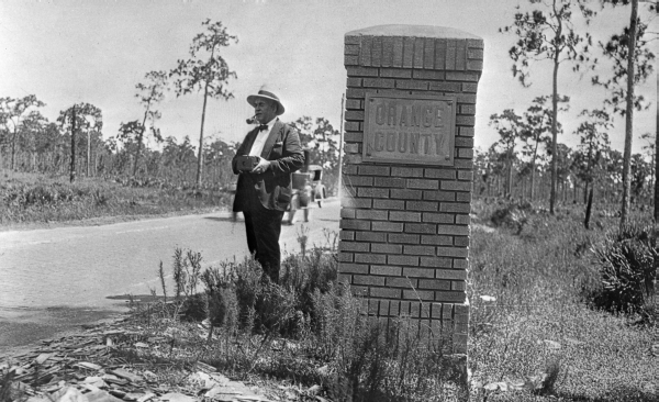 Surveyor A.C. Hart standing beside Orange County marker