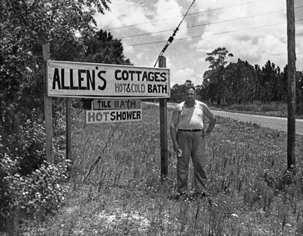 Virgil Allen standing beside advertising sign for his cottages - Panacea, FloridaPanacea, Florida