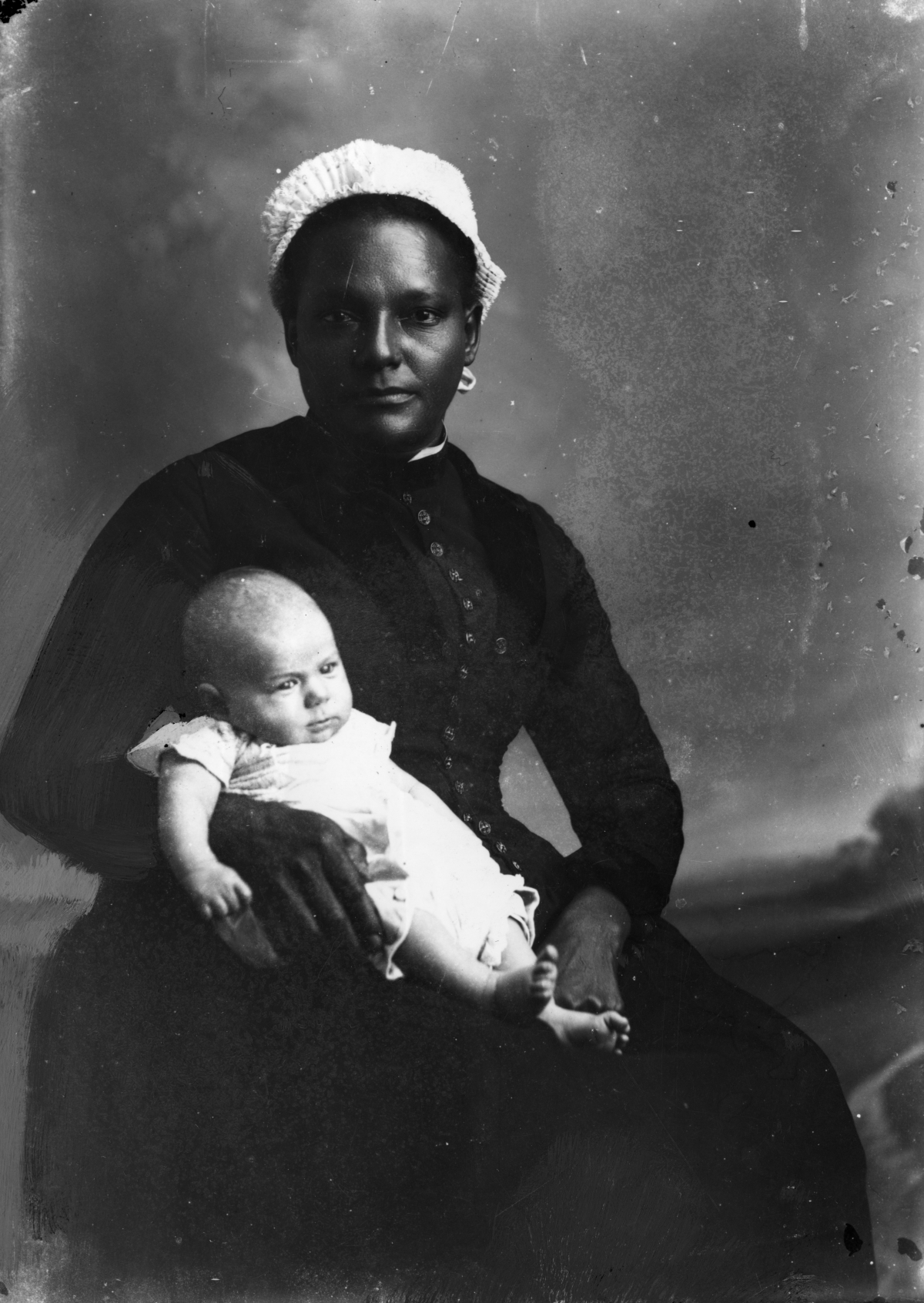 White-capped nurse holding an infant.