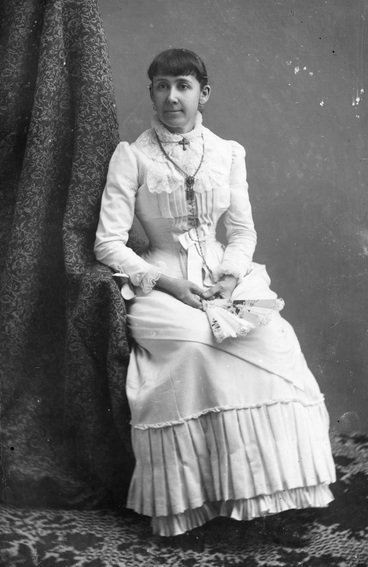 Unidentified woman in tiered dress, holding a fan.