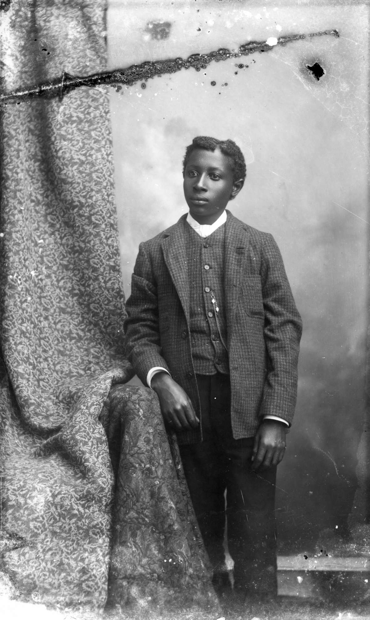 Young man in plaid coat and vest.