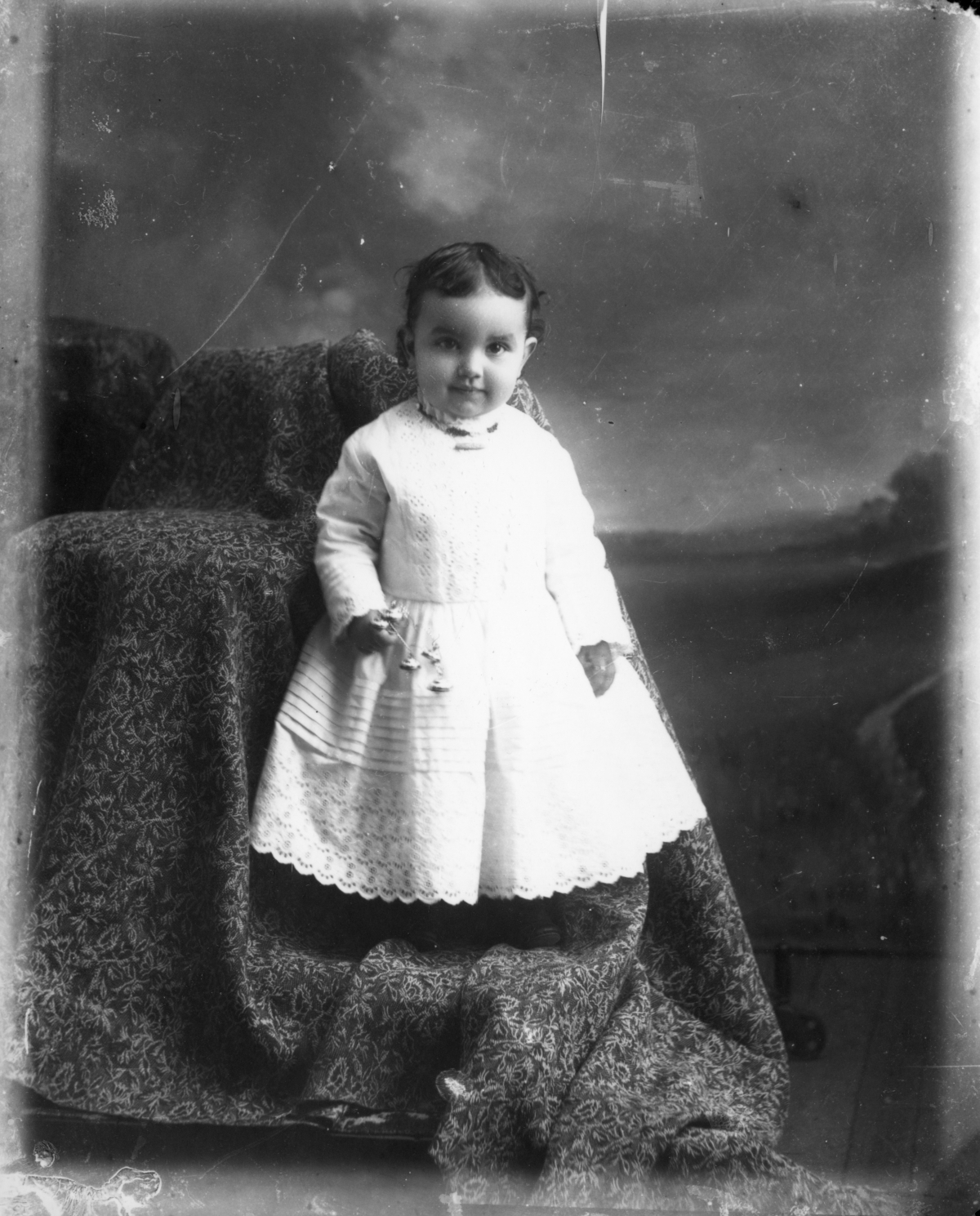 Standing child, holding a rattle.