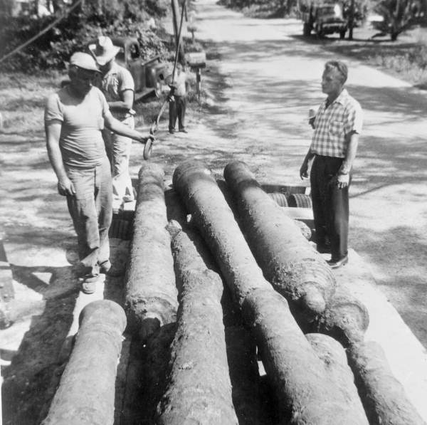 Treasure hunter Art McKee standing by cannons recovered from a shipwreck