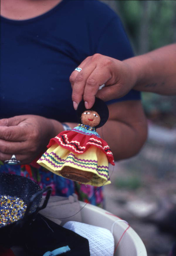 Seminole doll made by Mary Billie being held up for the camera: Big Cypress Seminole Indian Reservation, Florida