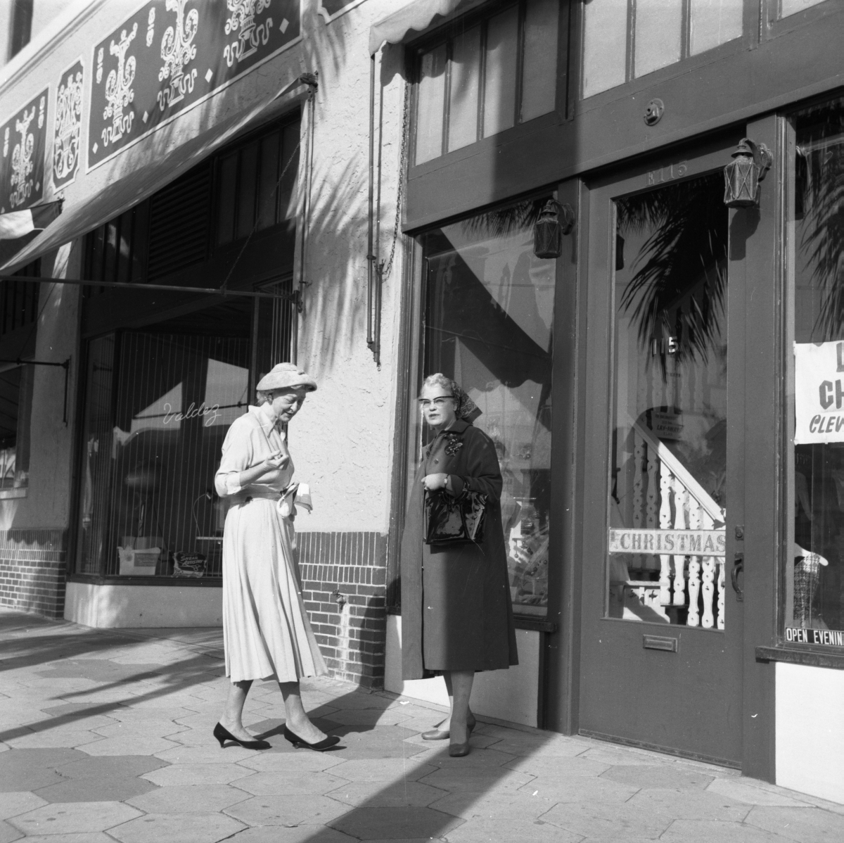 Two women standing on sidewalk in front of store