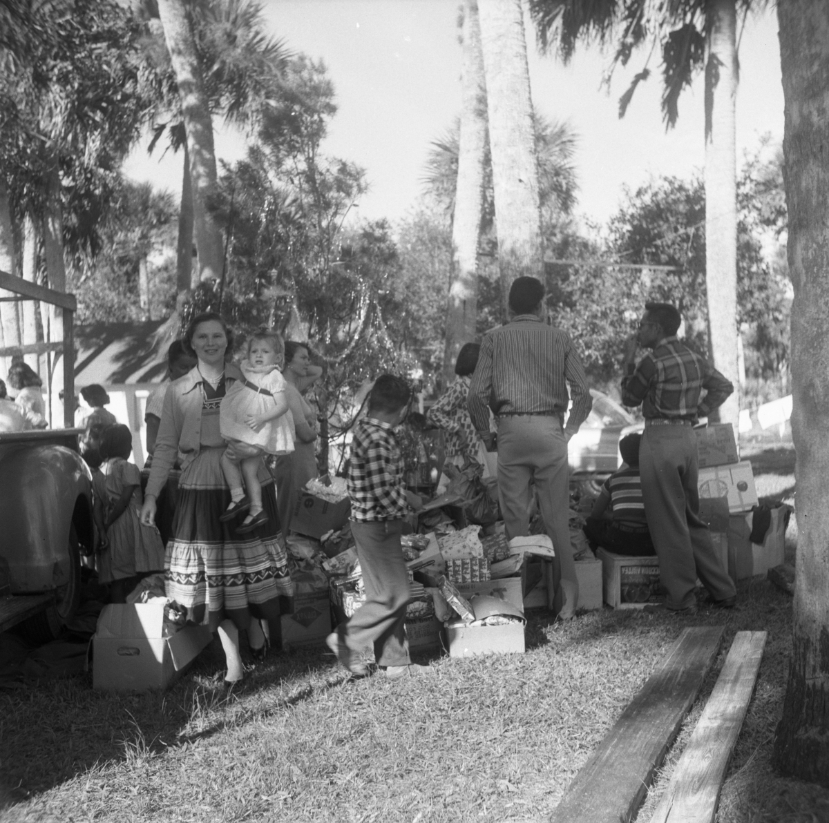 Group of people standing outside near a Christmas tree and opened packages
