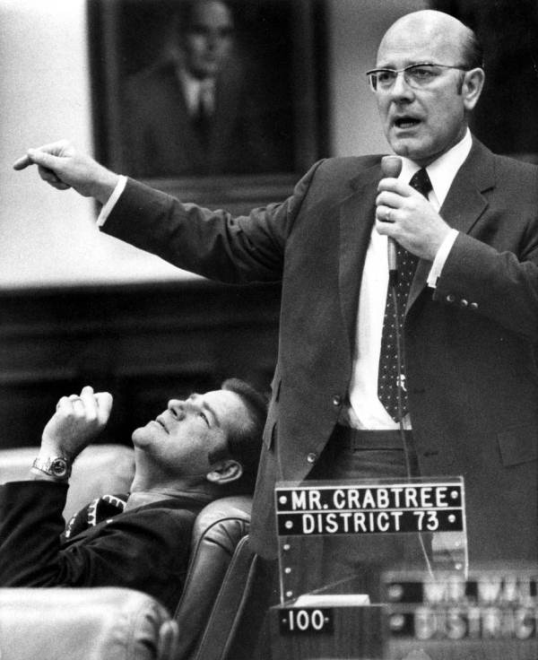 Representative Jim Foster gazing at Representative Granville Crabtree's finger.