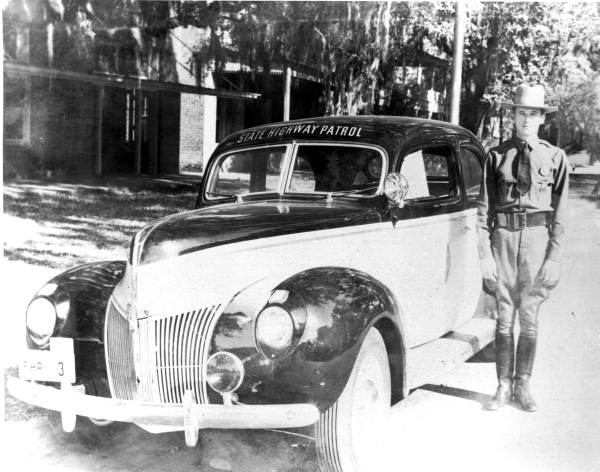 Portrait of Florida Highway Patrolman J. Wallace Smith standing next to his assigned patrol car.