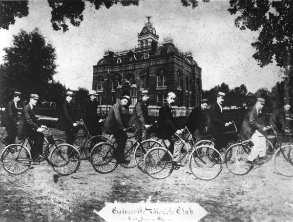 Gainesville bicycle club riding in front of the second county courthouse.