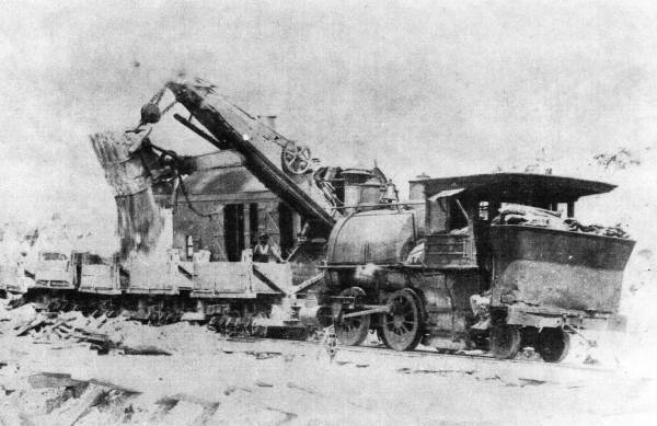 Steam shovel dumping ore into a freight car