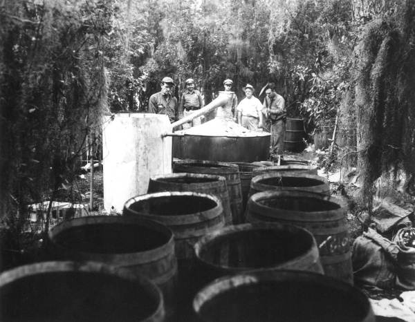 Sheriffs destroying distillery equipment.