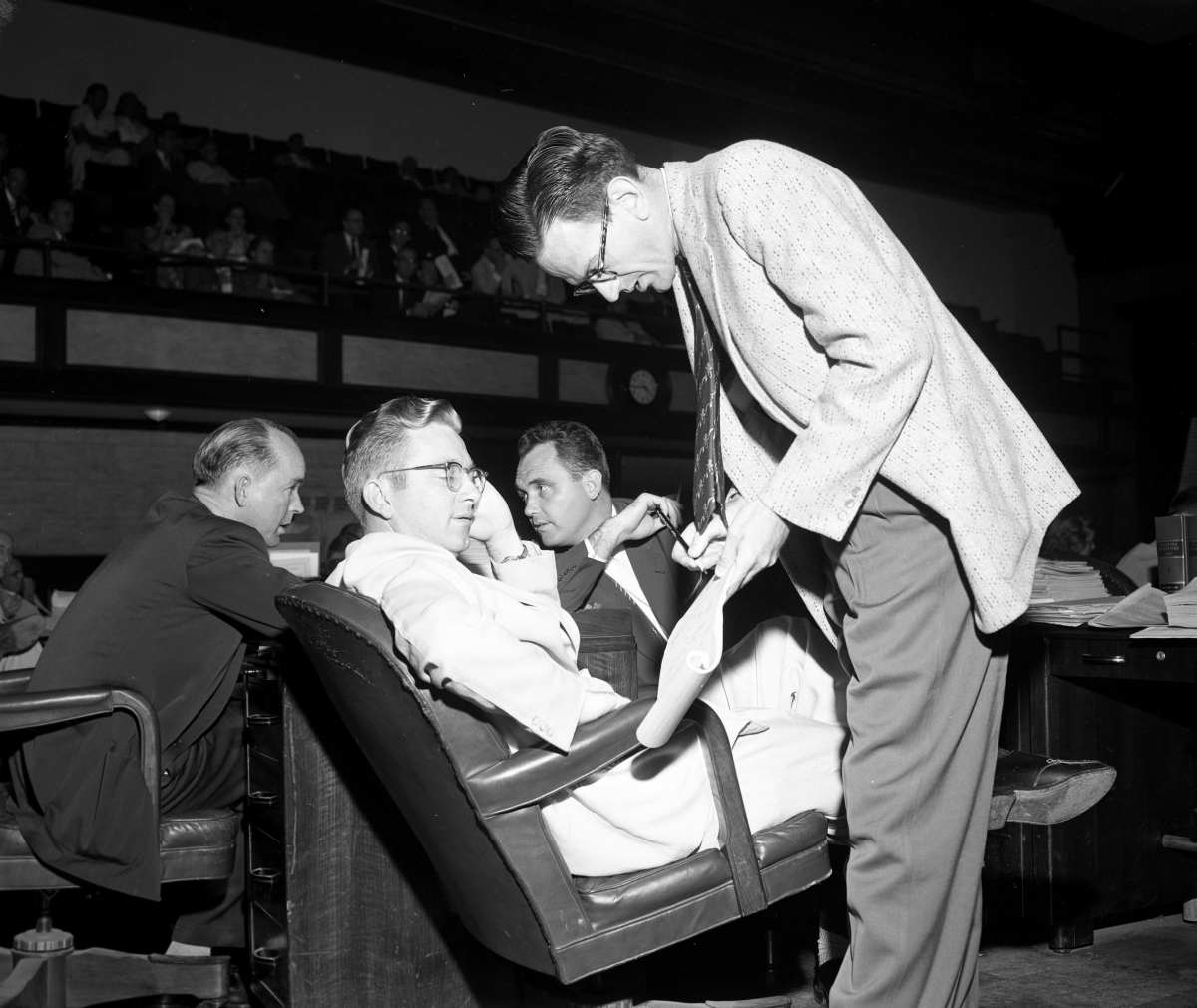 Men in legislature in a discussion at their desk