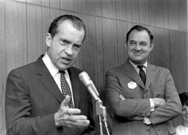 Governor Kirk listening attentively to former Vice-president Richard Nixon speaking at the microphone