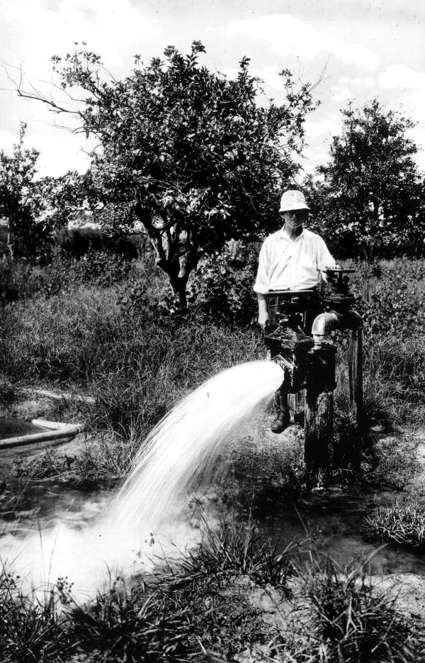 A man stands behind a flowing artesian well - Tampa, Florida.