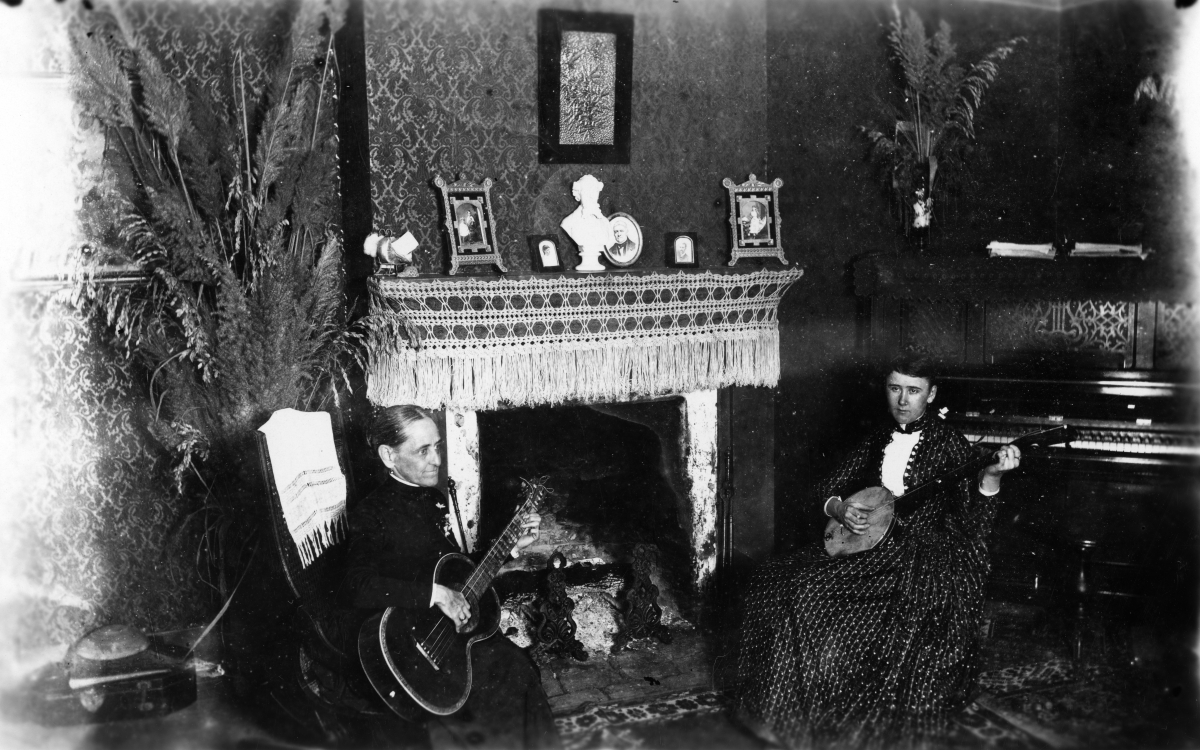 Women sitting by fireplace holding their musical instruments - Tallahassee, Florida.