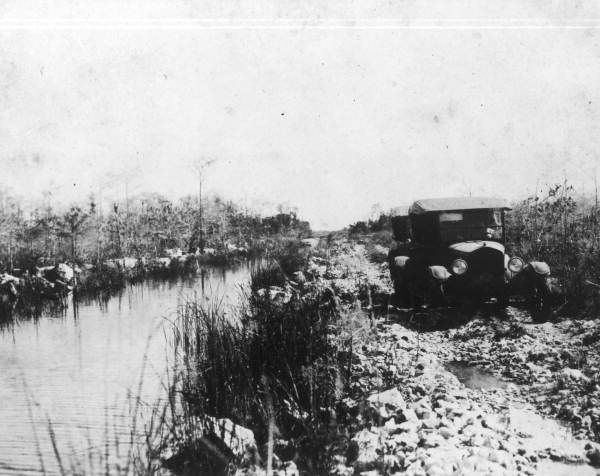 Two cars running on the road by canal - Tamiami Trail, Florida