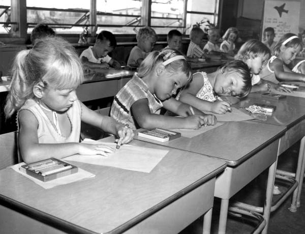 School children coloring at their desks in the classroom - Jacksonville, Florida.