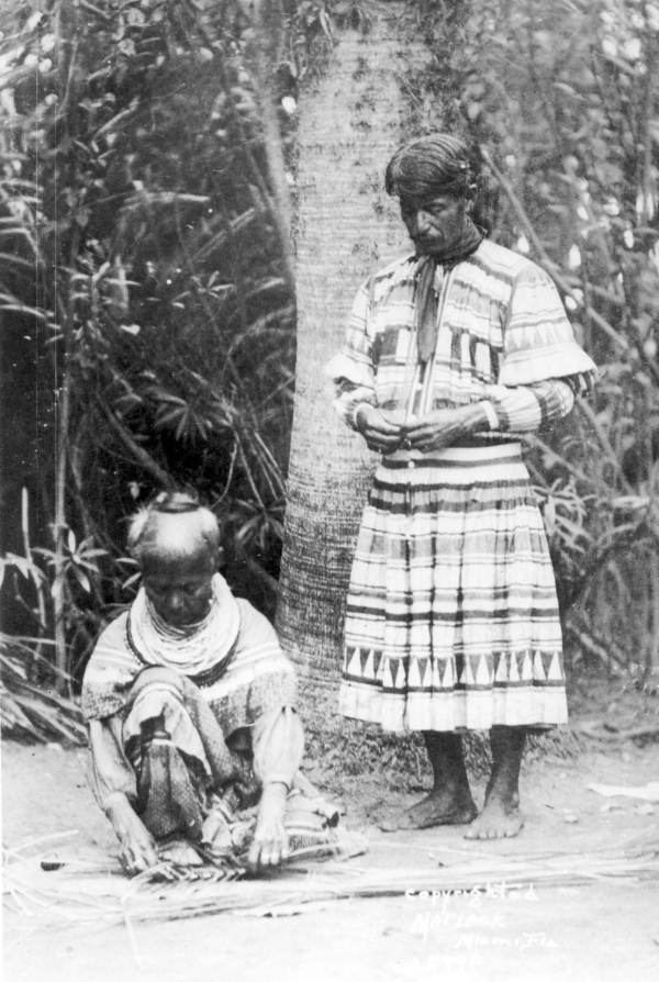 Man watching woman weaving fronds