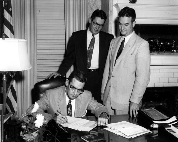 Governor Dan McCarty signing papers at his office - Tallahassee, Florida.