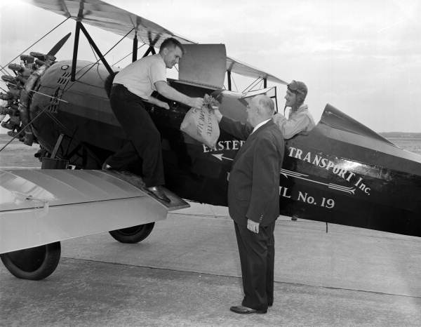 Man receiving "air mail" from bi-plane during Eastern Air Lines air show - Jacksonville, Florida.
