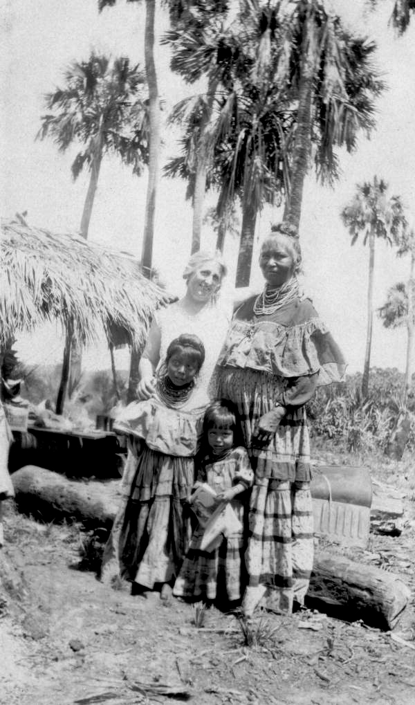 Unidentified midwife standing with Seminoles at a temporary camp in Immokalee, Florida.