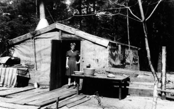 Young woman standing at the entrance to the family's tarpaper house.